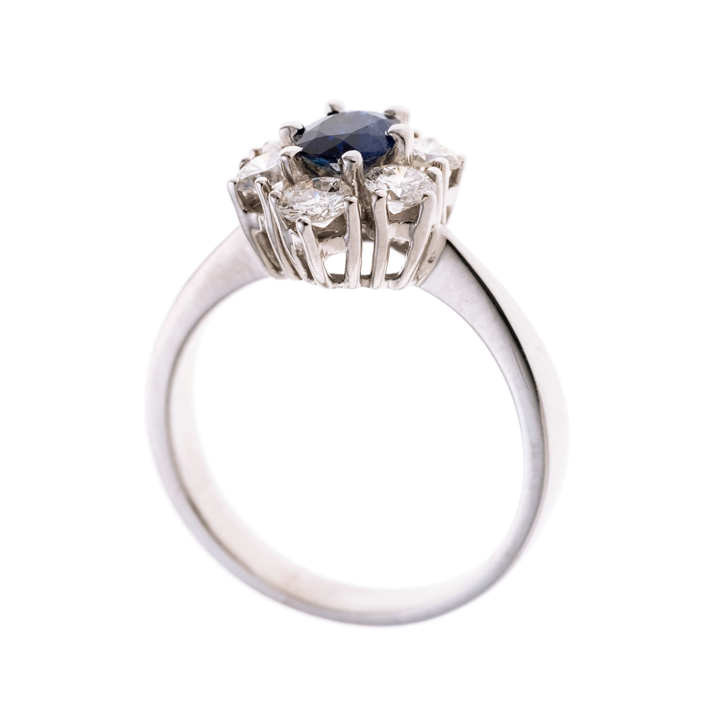 Ein Damenring gefertigt aus 585er Weißgold mit einem ovalen facettierten Saphir von ca. 0,6 ct und einer Entourage aus 6 Brillanten von zus. insg. 1,20 ct.