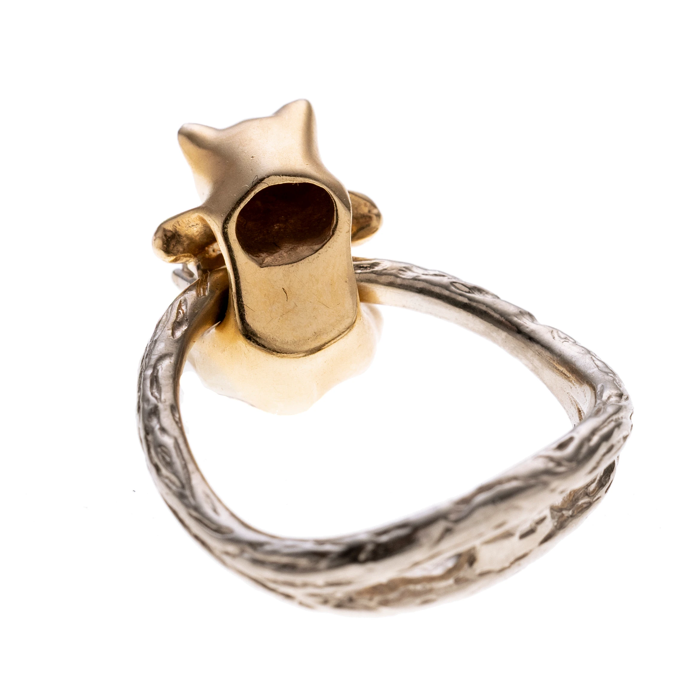 Weißgoldene Ringschiene gestaltet wie ein Ast, daran beweglich hängend befindet sich eine Katze mit einem Diamanten in der Hand.