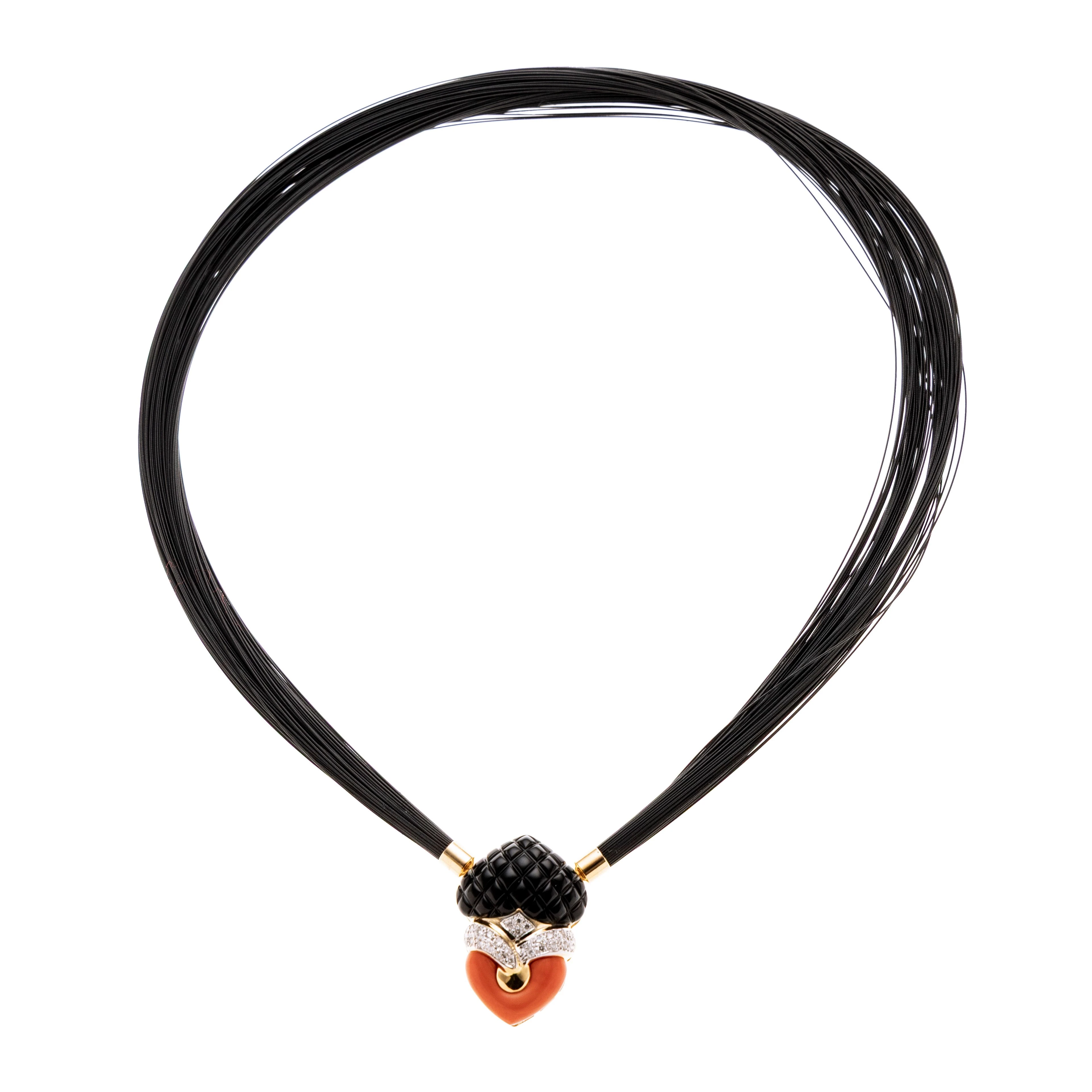 Dekorativer Anhänger in verflochtener Herzform. Aus Koralle und eine Onyx-Herz, dazwischen verflochten Gelbgoldelemente mit Diamantenbesatz.  An einem mehrreihigem schwaren Reif, Bajonettverschluss. Seitlich 3 verschiedene Bajonettaussparungen, um den Reif variabel anbringen zu können.