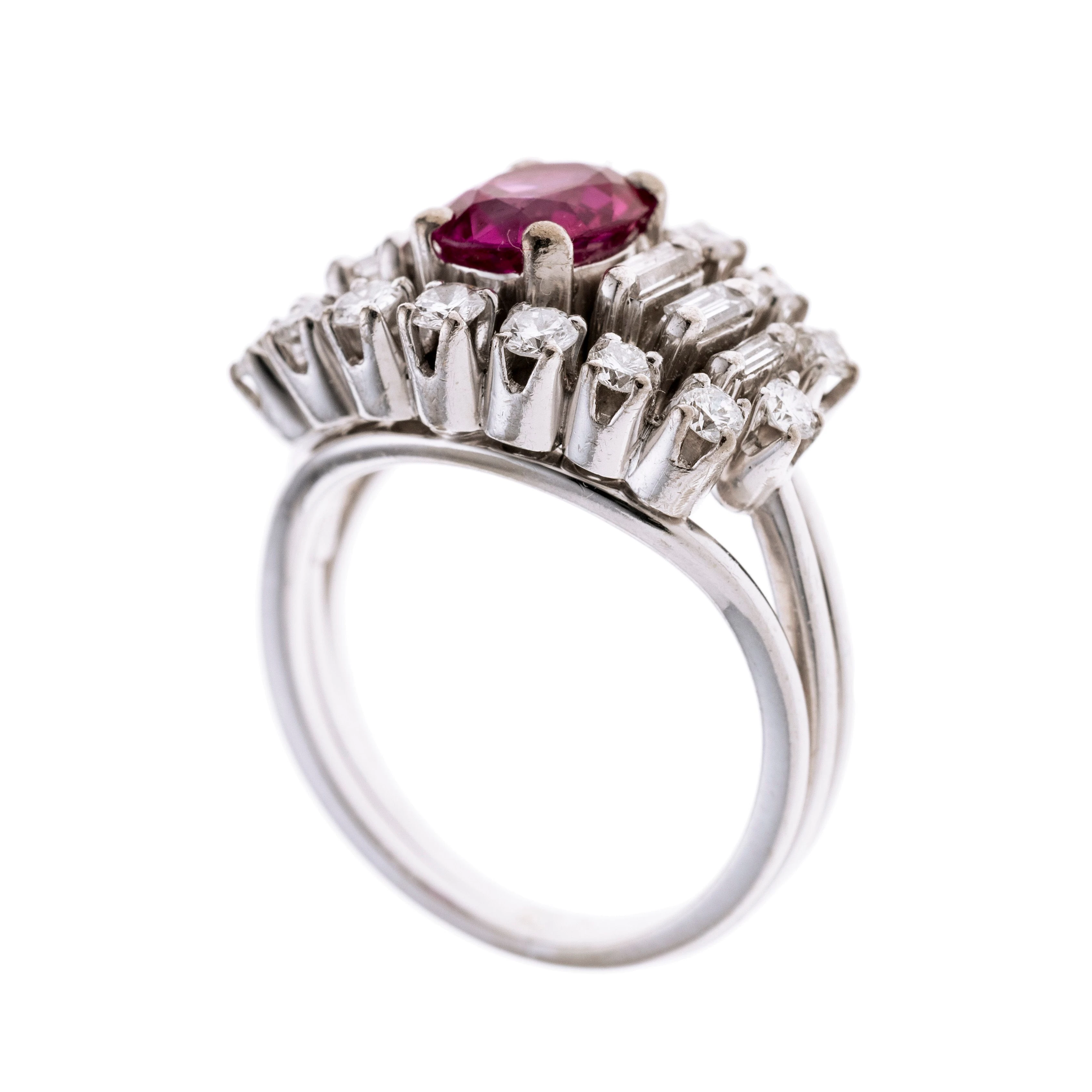 Mittig sitzt ein Rubin (Burma) in vier Krappen gefasst, flankiert von sechs Baguette Diamanten, gerahmt von Brillanten in Krappenfassungen. Die Ringschiene ist in drei geteilt.