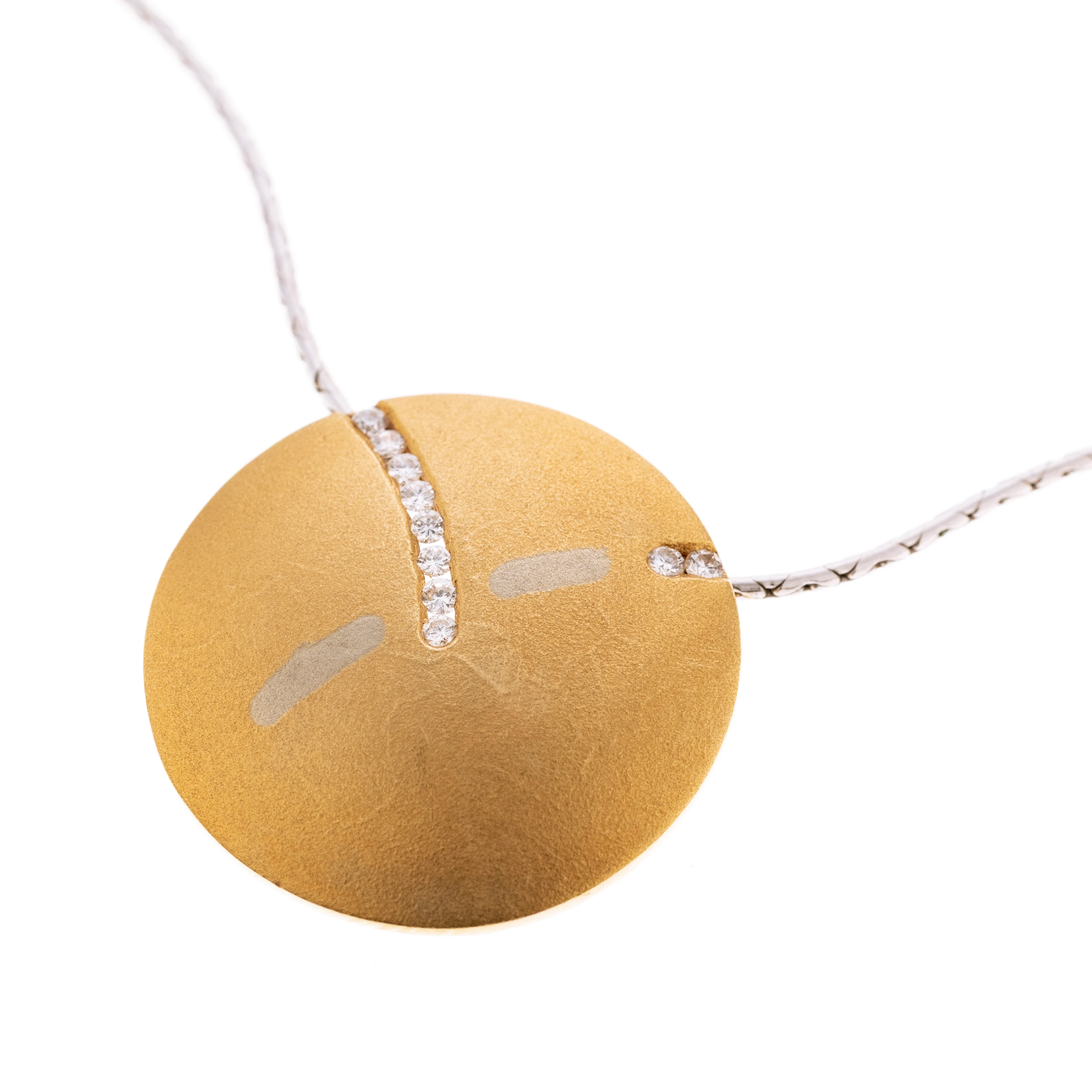 Eine gelbgoldene Scheibe mit einen Streifen aus 8 Brillanten und einem aus zwei Brillanten, an einer weißgoldenen Kobrakette.