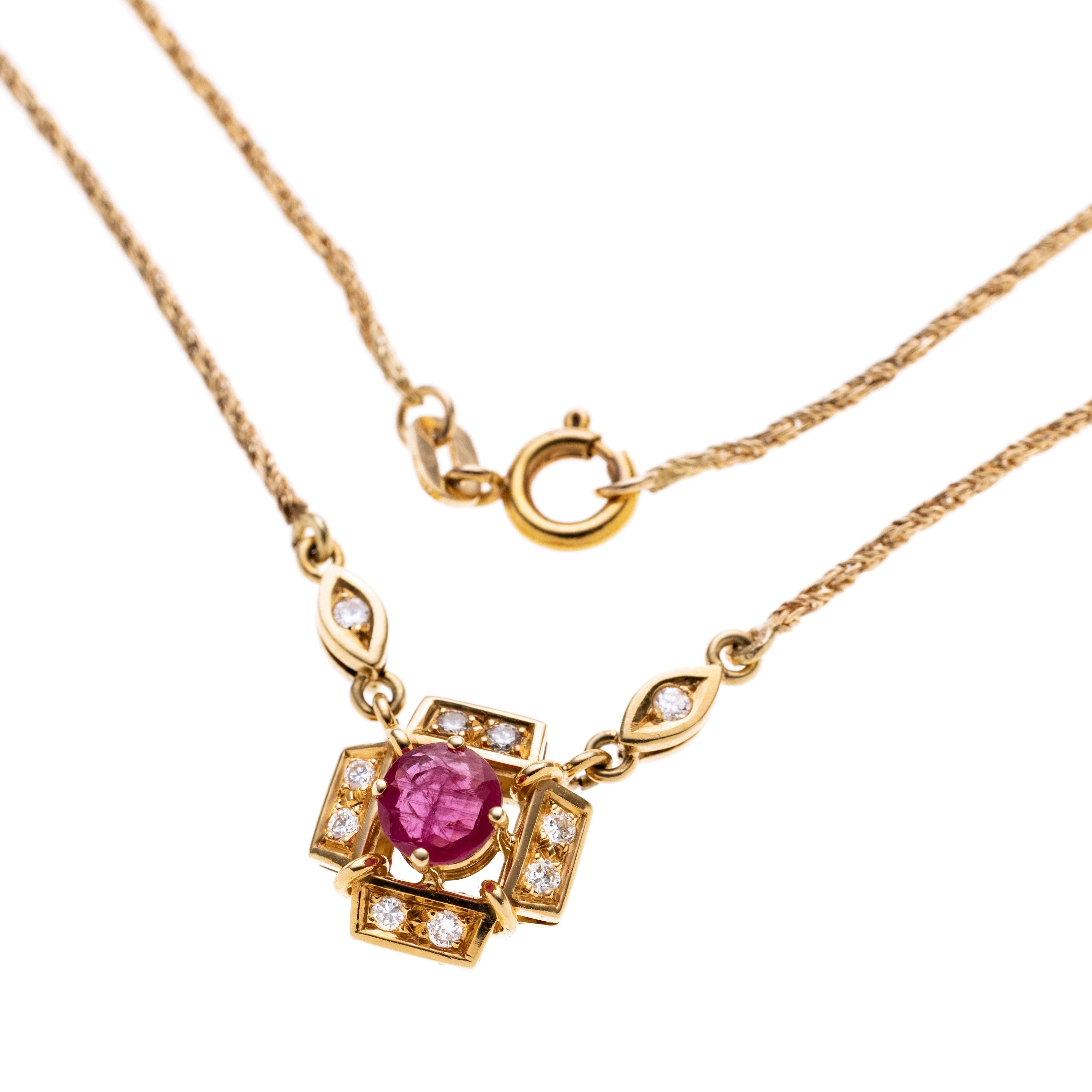 Ein kreuzförmiger Anhänger mit mittig einem Rubin, der zusätzlich mit insgesamt acht brillanten besetzt ist. An einer Kordelkette mit zwei navetteförmigen Elementen zum Anhänger hin die mit zwei Brillanten besetzt sind.