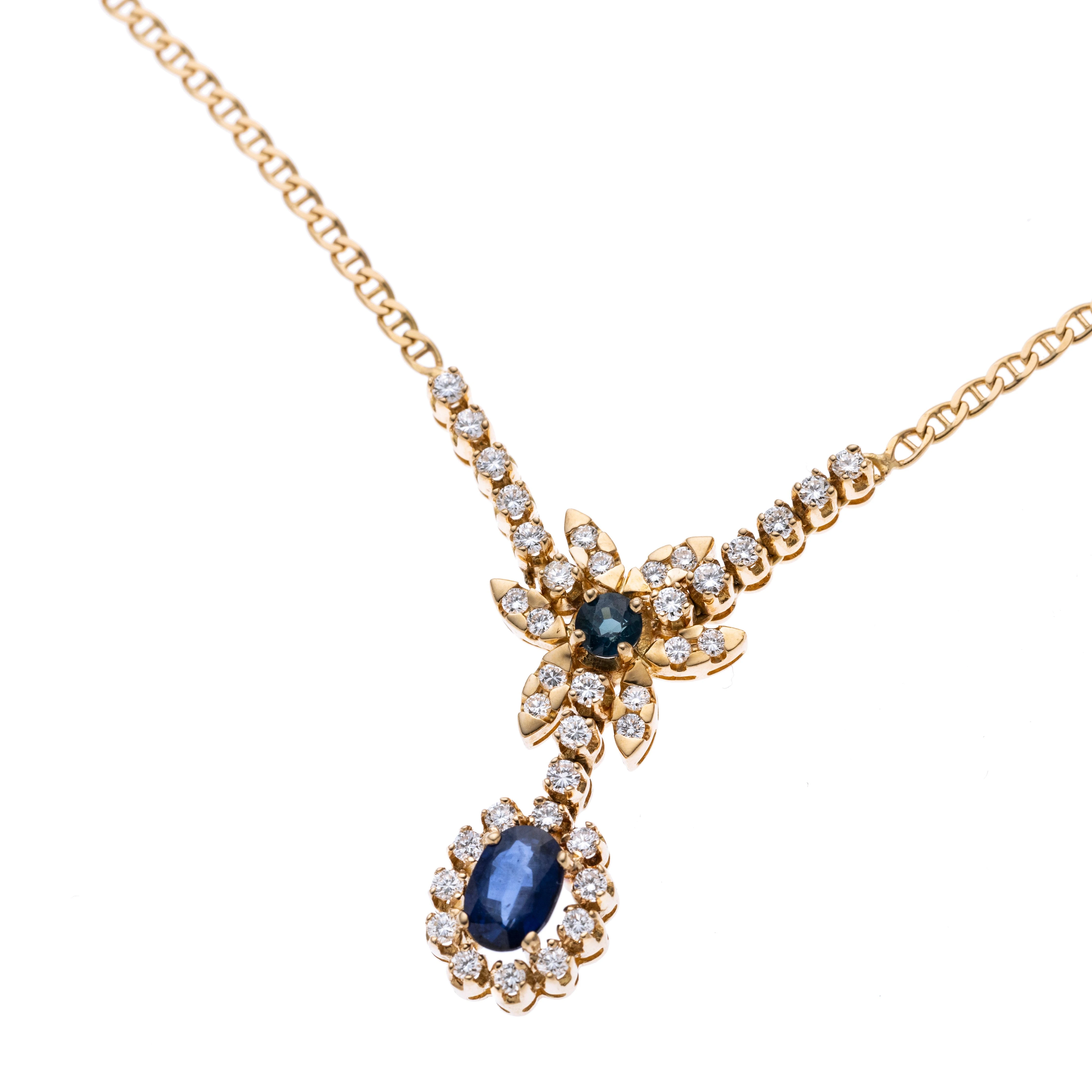 Eine Blüte mit Diamantenbesatz und einem Saphir ca. 0.31 ct. als Mittelstein. Daran abgehängt wurde ein ovaler, von elf Diamanten karmoisierter, ca. 1.35 ct. Saphir. Das Blütenelement befindet sich zwischen insgesamt zwölf Brillanten à ca. 0.03 ct., die in Krappen gefasst wurden.