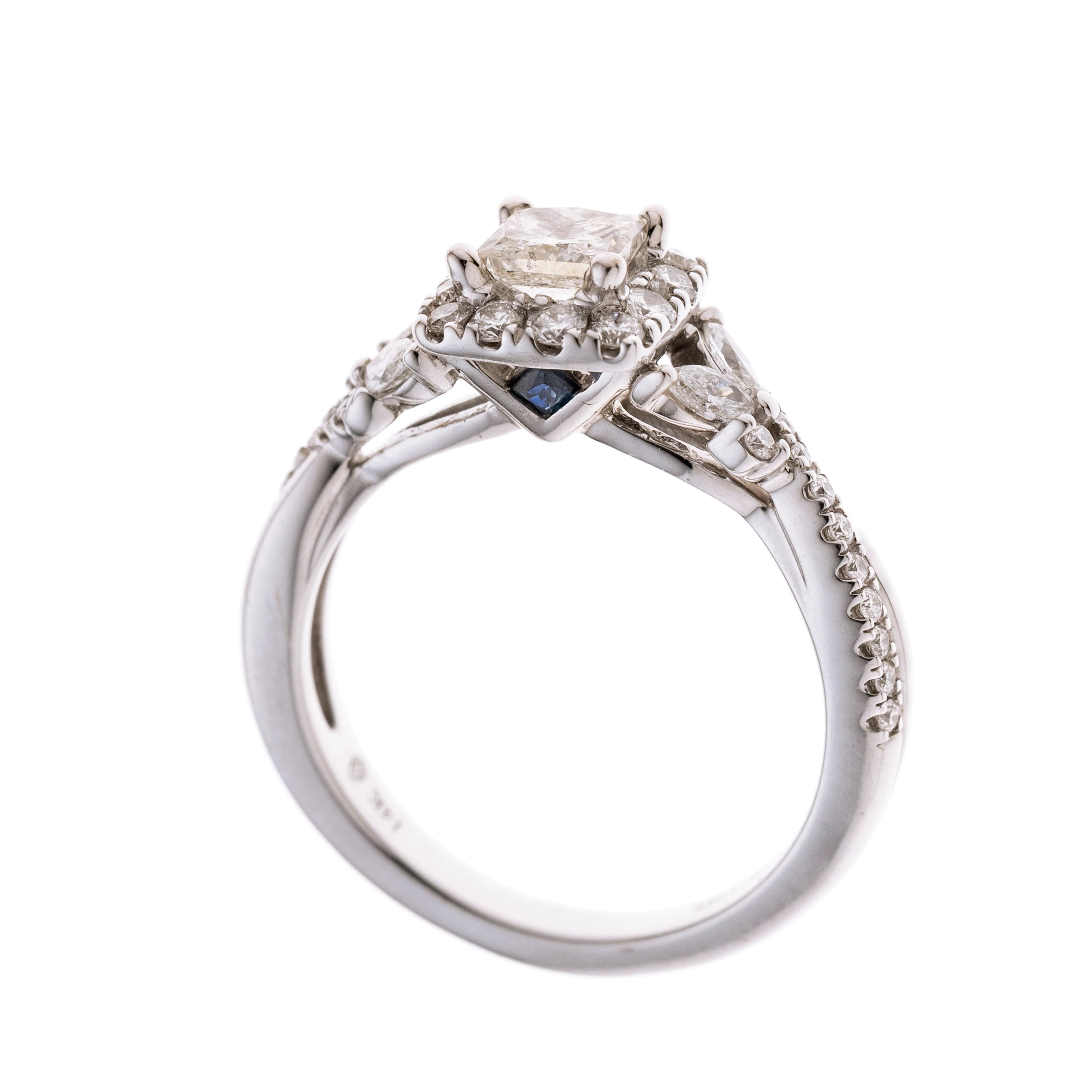 Ein Halo-Ring aus der Vera Wang Love Collectiion mit insgesamt 1 ct Diamanten. Der ca. 0.50 ct Pincess-Cut Diamant wird von 12 Brillanten gerahmt. In der Galerie wurden zwei Saphire ebenfalls im Princess-Cute eingearbeitet. Die Ringschultern sind überkreuzend, geschwungen gearbeitet und mit insgesamt 20 Brillanten besetzt welche in je zwei Navette-Diamanten enden. Signiert "Vera Wang."