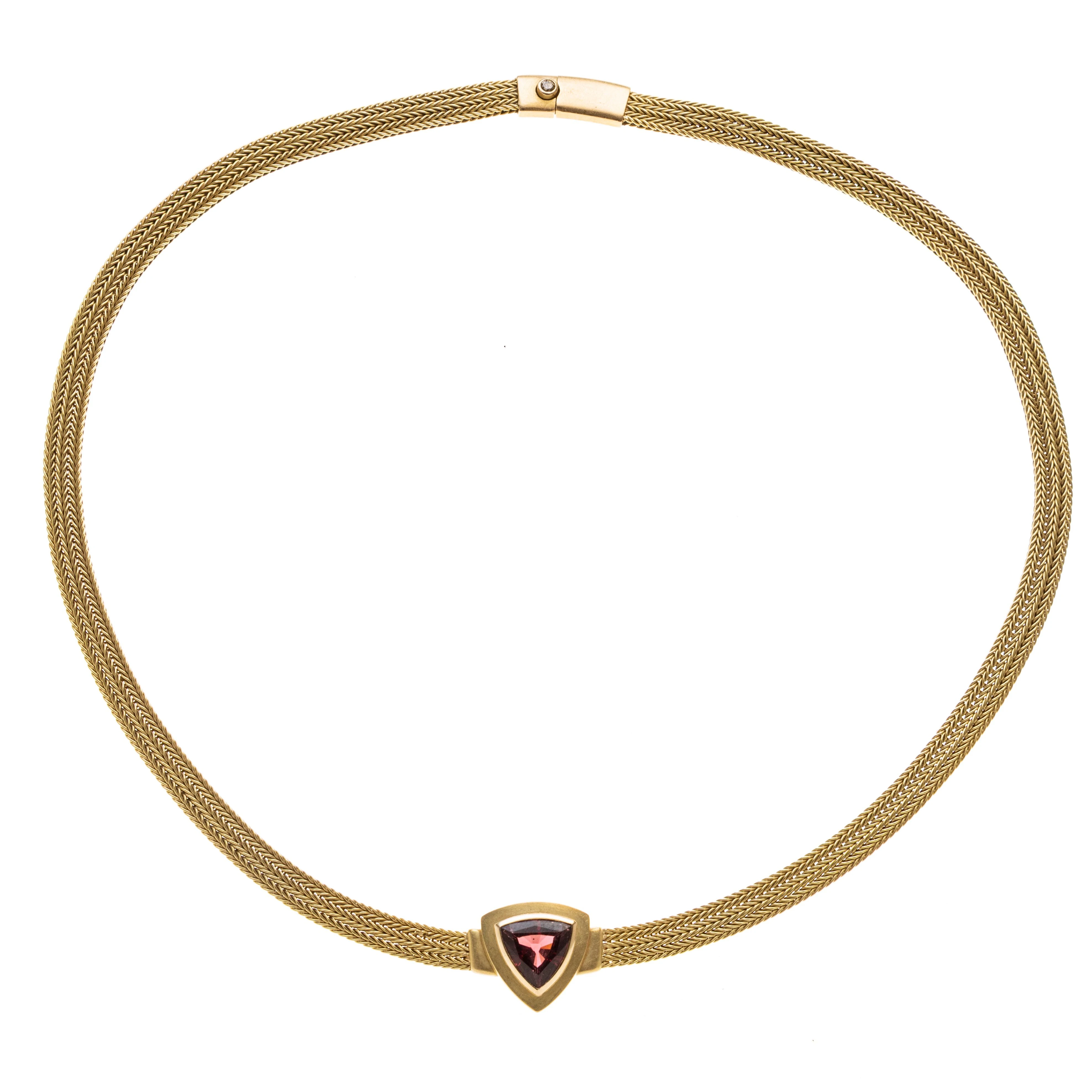Ein Collier, flache 3-reihige Fuchsschwanzkette mit Kastenschloß, mittig ein triangelförmiger Rubellit in Zargenfassung in die Kette eingearbeitet. Der Drücker des Kastenschlosses ist besetzt mit einem Diamant in Zargenfassung.