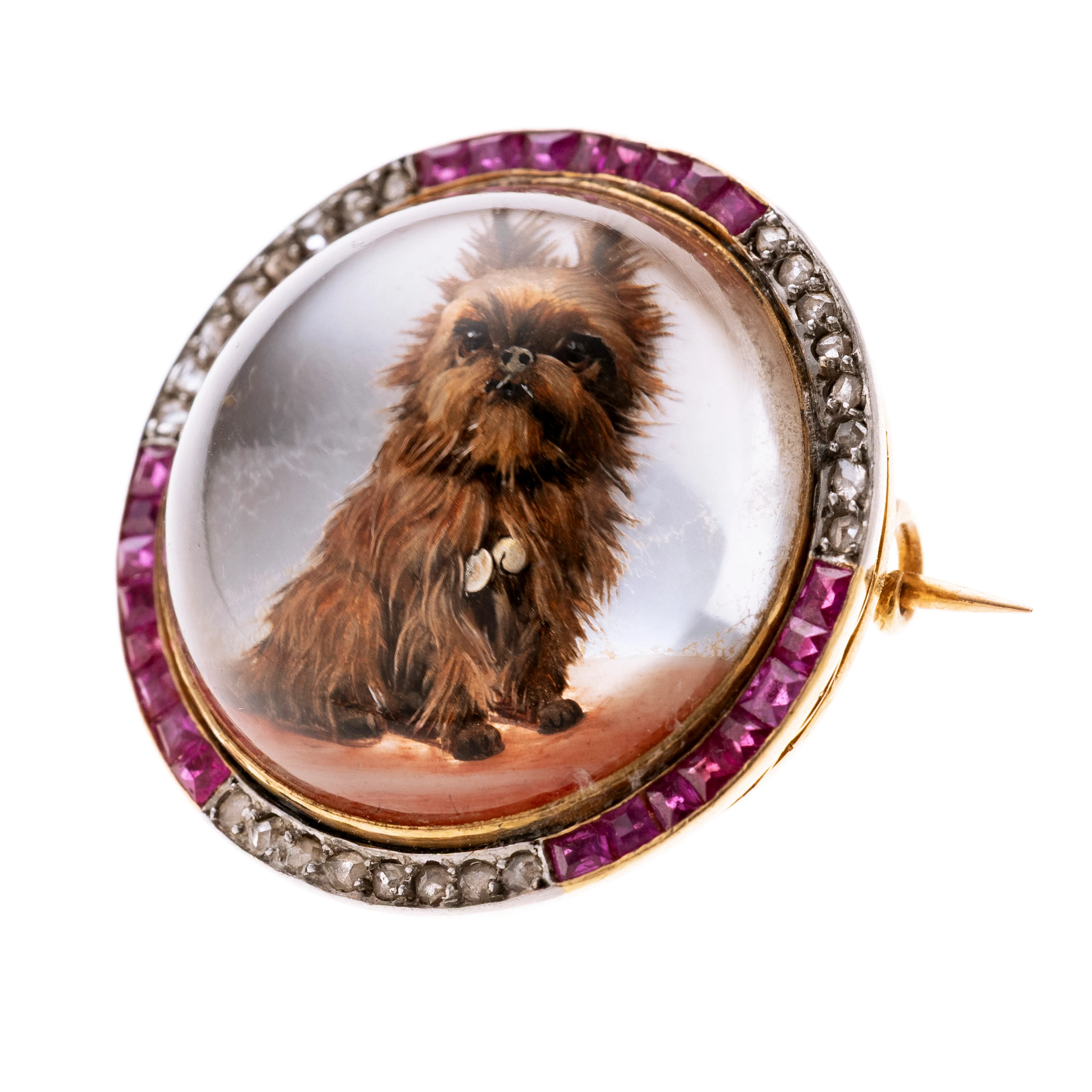 Rund mit mittig einem Essesx-Kristal aus Bergkristall mit der Darstellung eines "Naughty Terrier". Gerahmt wird dieser Cabochon von drei Abschnitten mit Rubin -Carrées und drei Abschnitten mit Diamantrosen. Eine exquisite Hommage an den besten Freund des Menschens. Breite 2,5 cm.