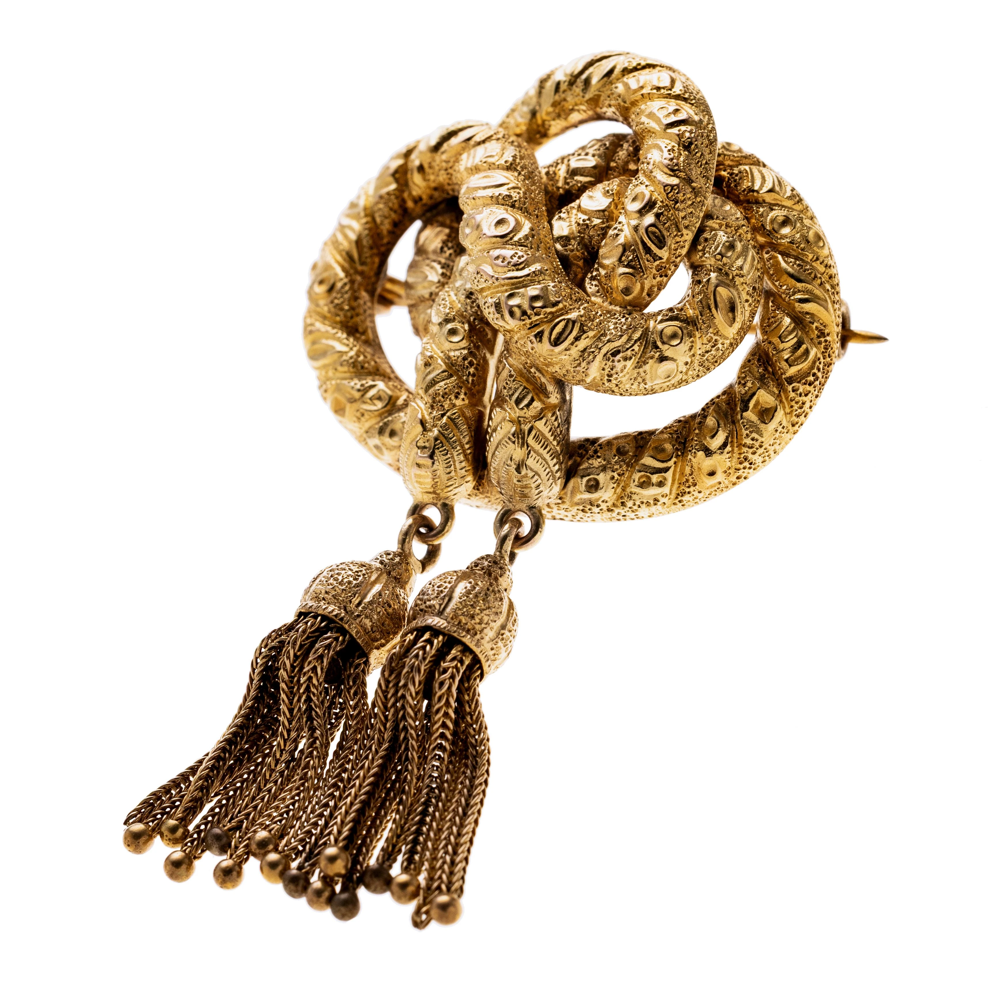 Eine Knoten-/Schlangenbrosche, ziseliert mit zwei abgehängten Quasten aus 750er Gold.