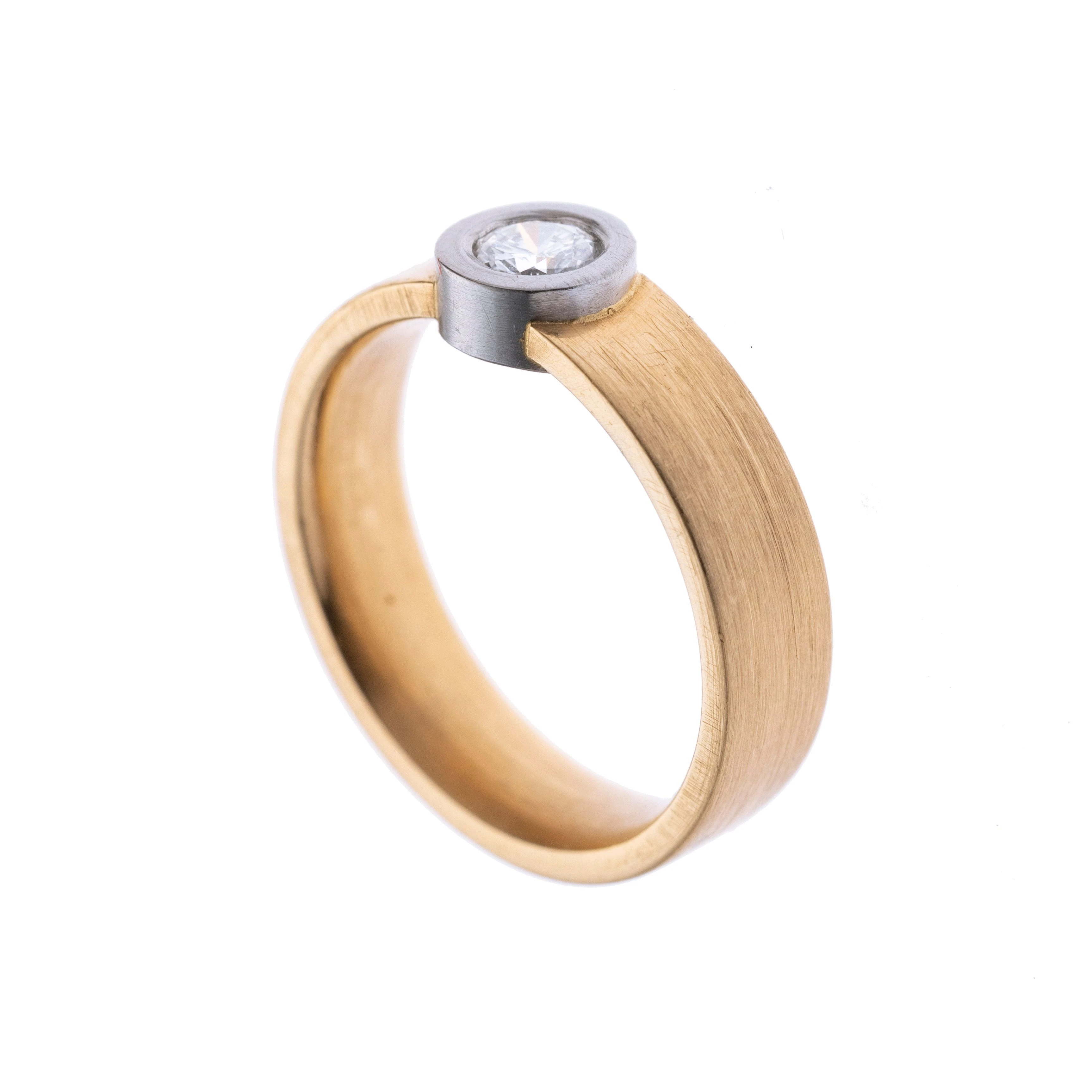 Ein breiter Solitärring mit einem in Weißgold gefassten Diamanten. Die Ringschiene ist mattiert. Signiert.