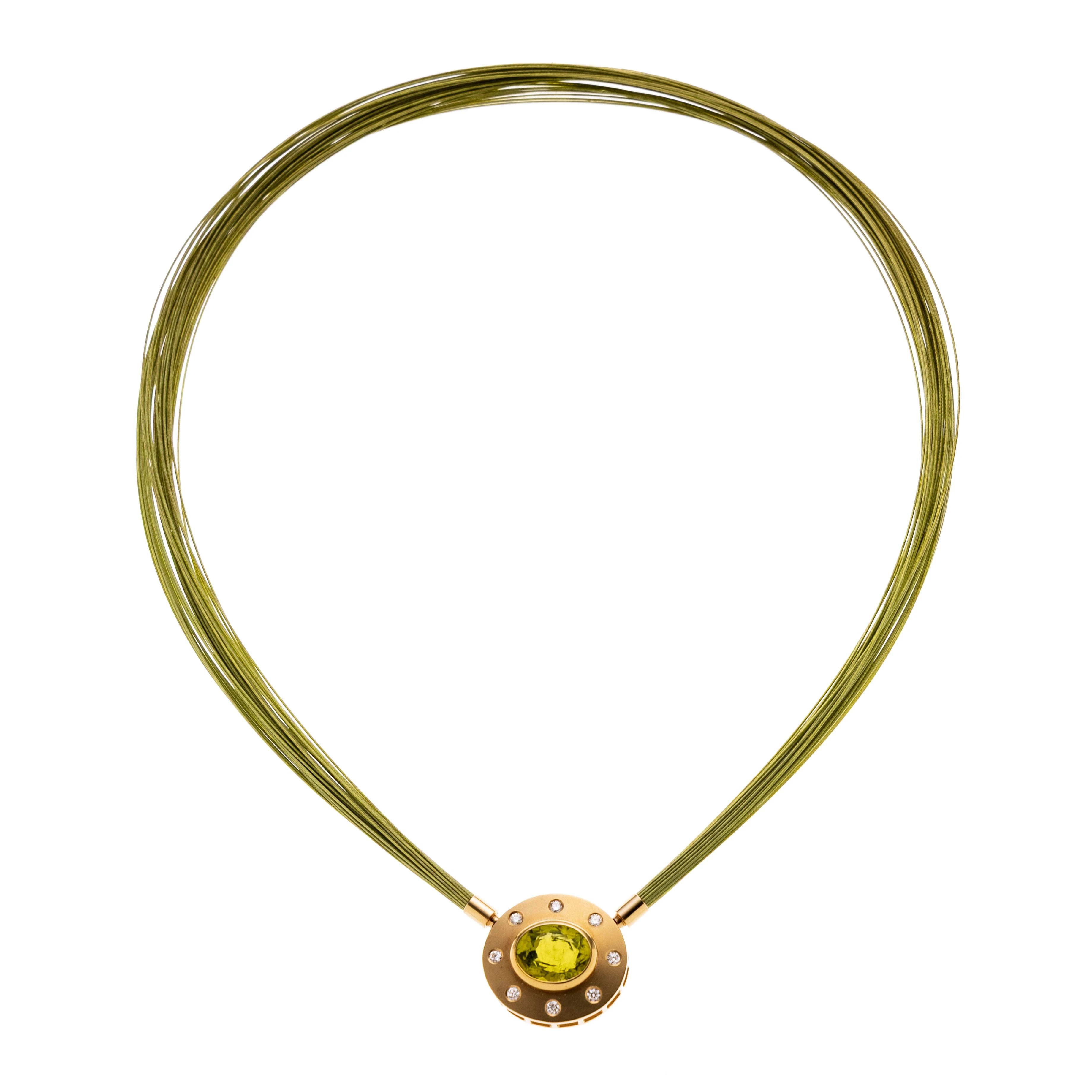 Ein ovaler mattierter Anhänger mit acht eingeriebenen Brillanten je ca. 0.03 ct. Mittig ein ovaler Peridot in Zargenfassung. Signiert StA. An einem mehrreihigen grünem Reif, Bajonettverschluss.