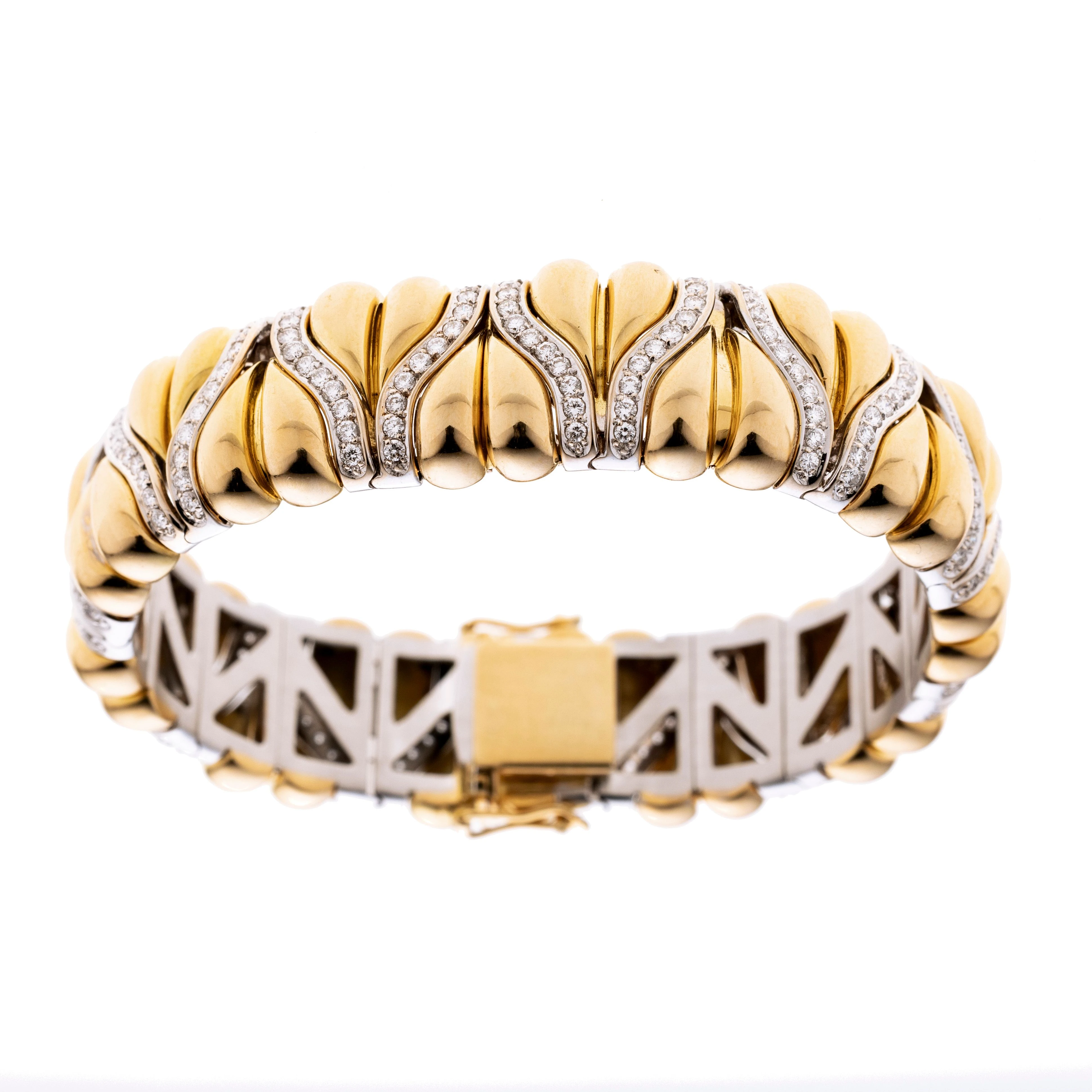 Gelbgoldene Herzelemente zwischen geschwungenen weißgoldenen mit Diamanten besetzten Elementen.