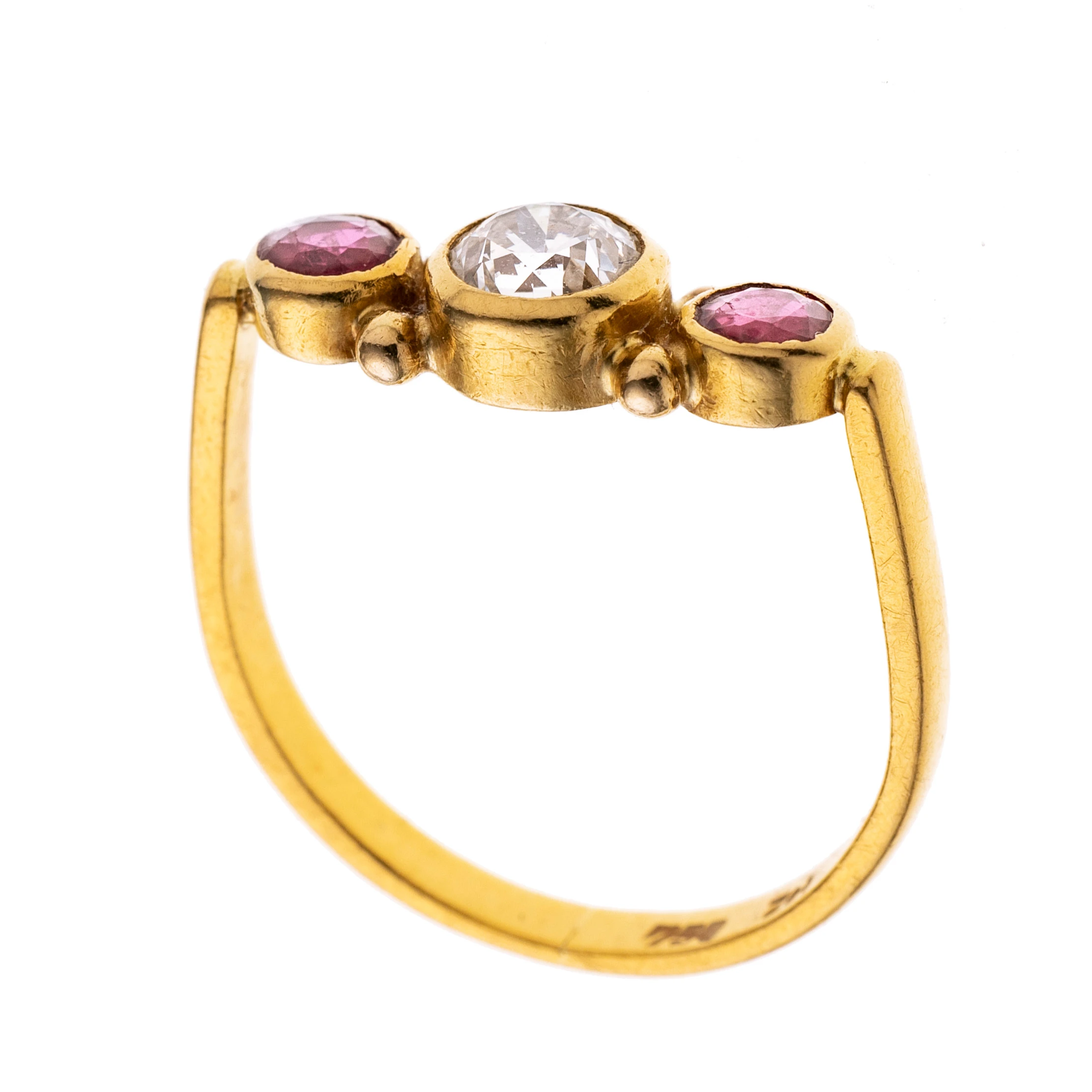 An einer u-förmigen Ringschiene befindet sich ein Ringkopf der mittig einen Altschliff-Diamant flankiert von je einem Rubin in Zargenfassungen in einer Linie. Signiert "Zet".