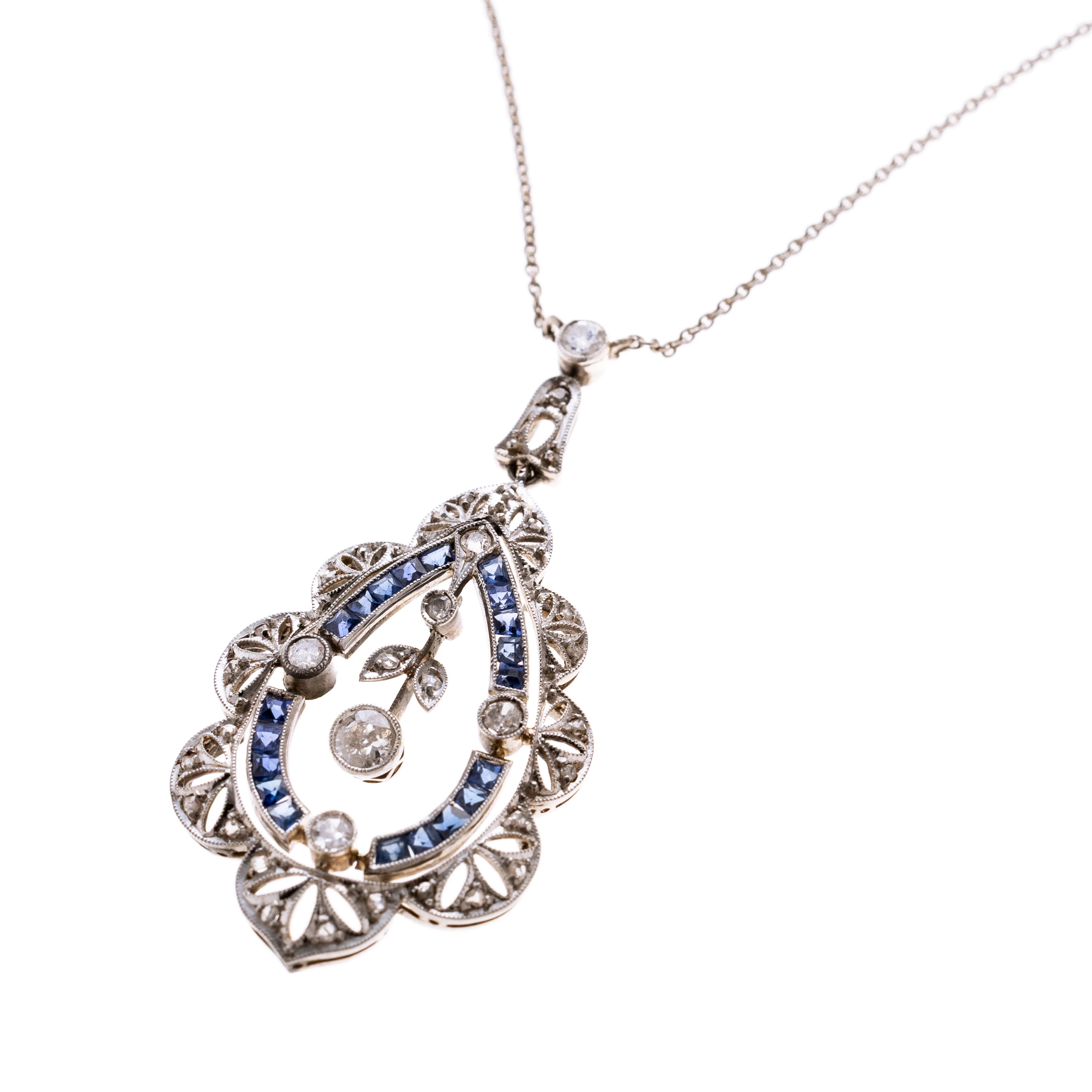 Tropfenförmiger, Diamantenbesetzter Anhänger, platiniert mit floraler Ornamantik. Mittig mit einr abgehängten Beweglichen Blume mit einem ca. 0.12 ct Altschliffdiamant. Gerahmt wird diese durch Saphire. An einer Ankerkette.