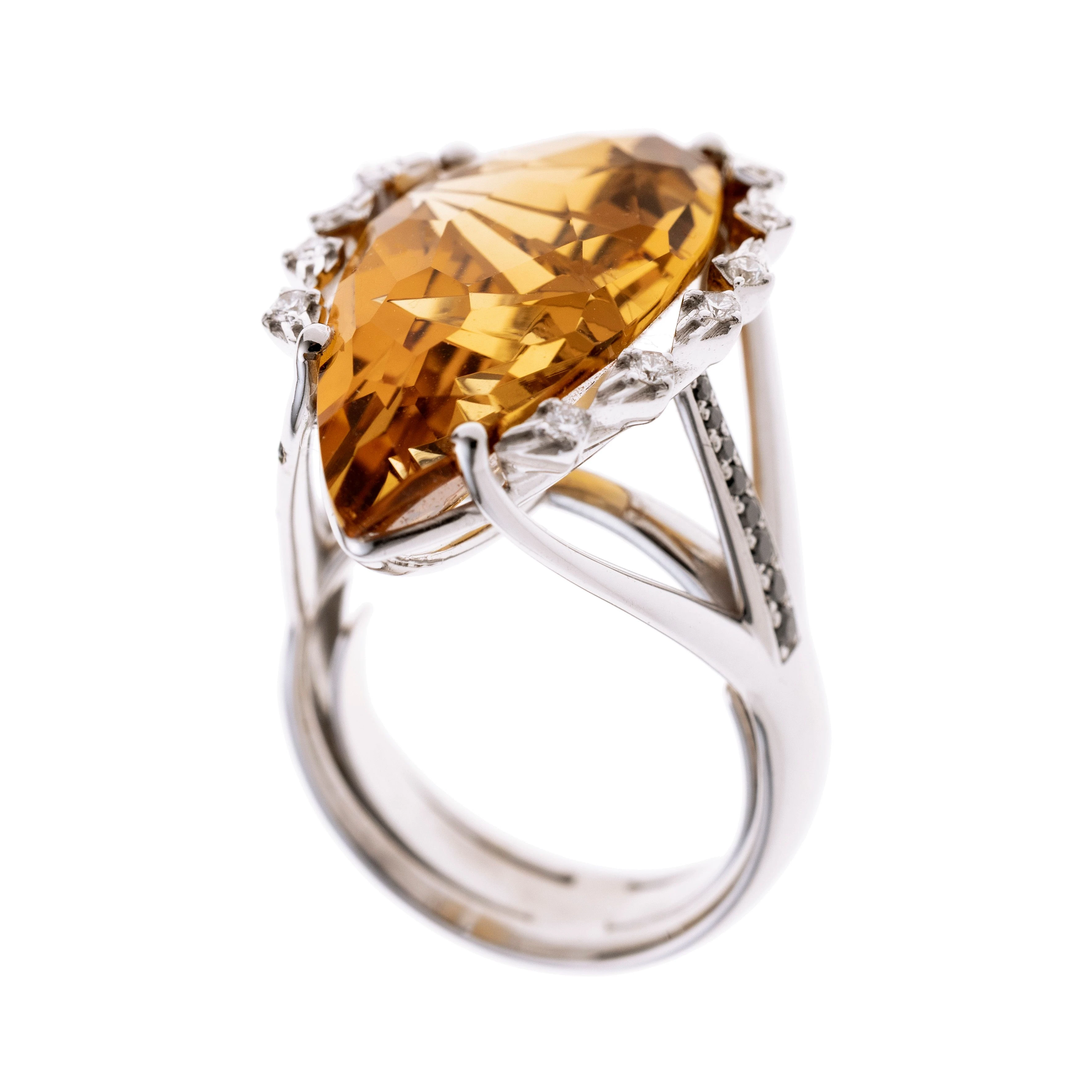 Ein Citrin im Fantasieschliff (nach Atelier Munsteiner) in vier Krappen gefasst flankiert von 10 Brillanten und an den Ringschultern sind Asymmetrisch insgesamt 18 schwarze Diamanten gesetzt.