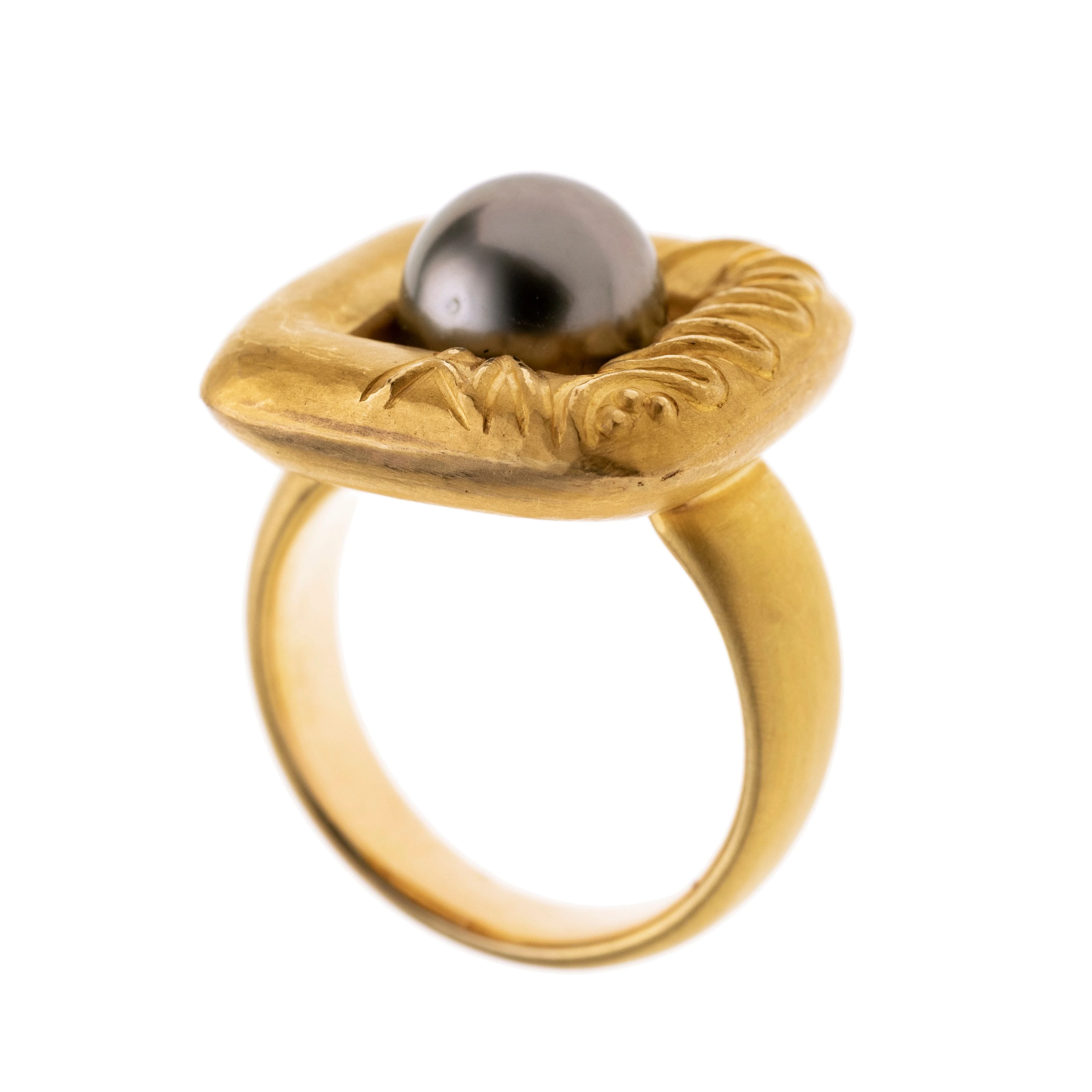 Massiv gearbeiteter Ring, mattiert mit quadratischem Ringkopf, der einseitig Ornamente aufweist. Mittig eine Tahitiperle (9,6 mm)