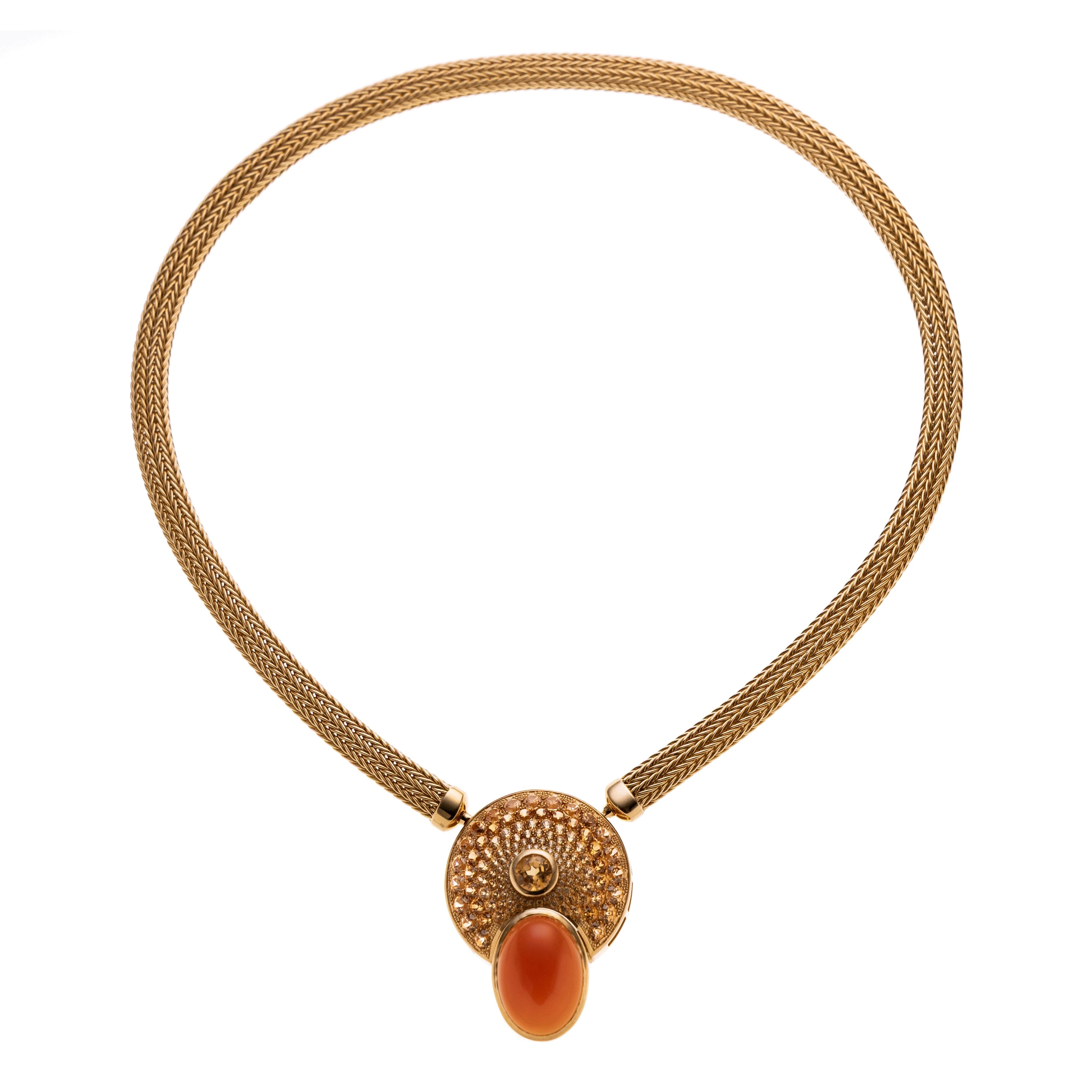 Ein runde Anhänger paveé besetzt mit orangefarbenem Granat (Mandarin-Granaten), den Abschluss bildet ein in Zarge gefasster Karneol. An einer Strickkette mit beidseitigen Bajonettverschluss.